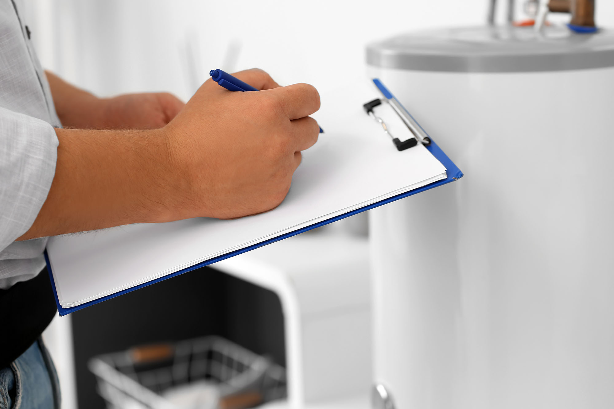 Male plumber with clipboard installing boiler in bathroom, closeup